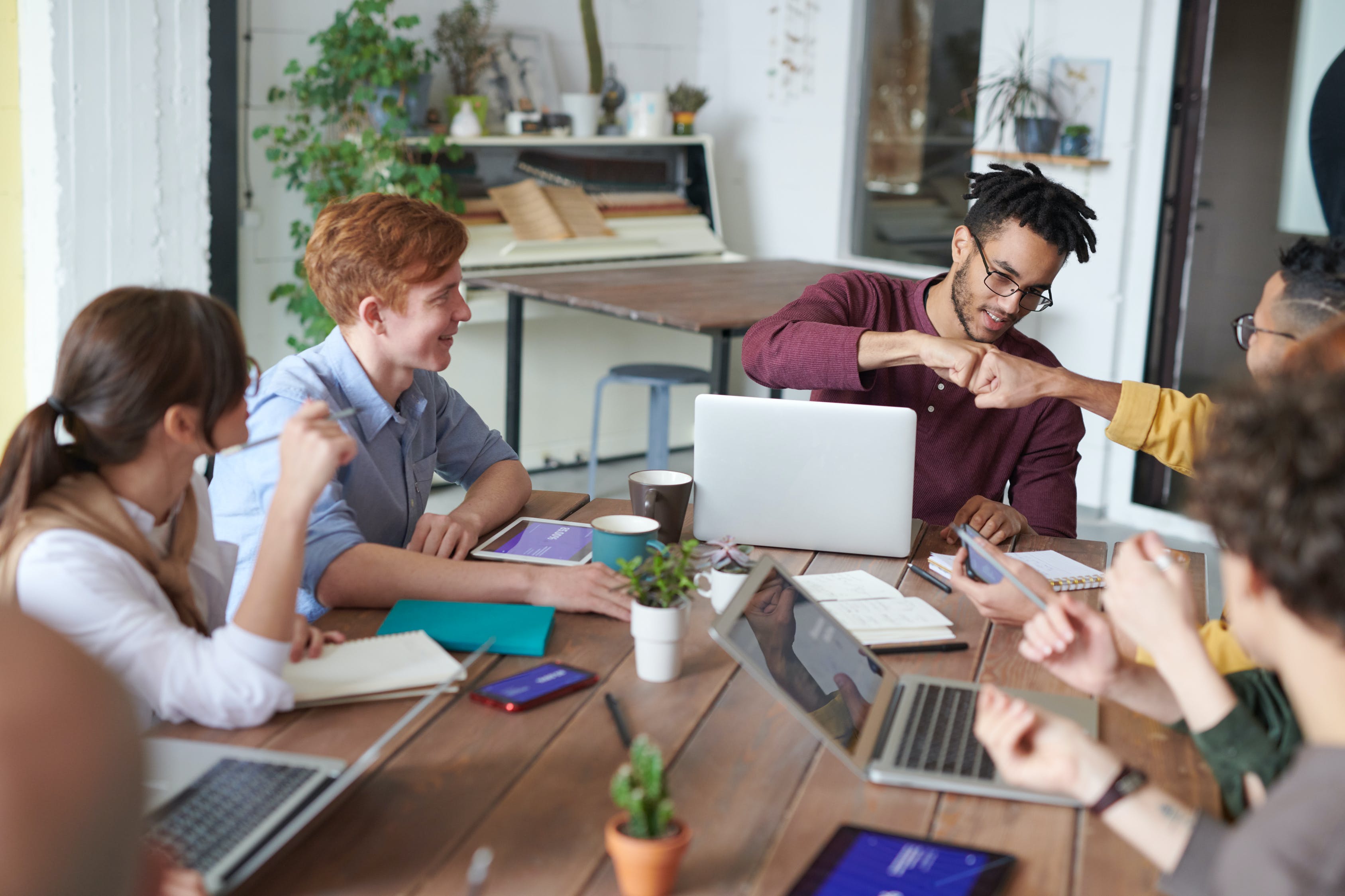 Young people sitting at a table smiling, One pair are doing a fist pump. Young people sitting at a table smiling, One pair are doing a fist pump.