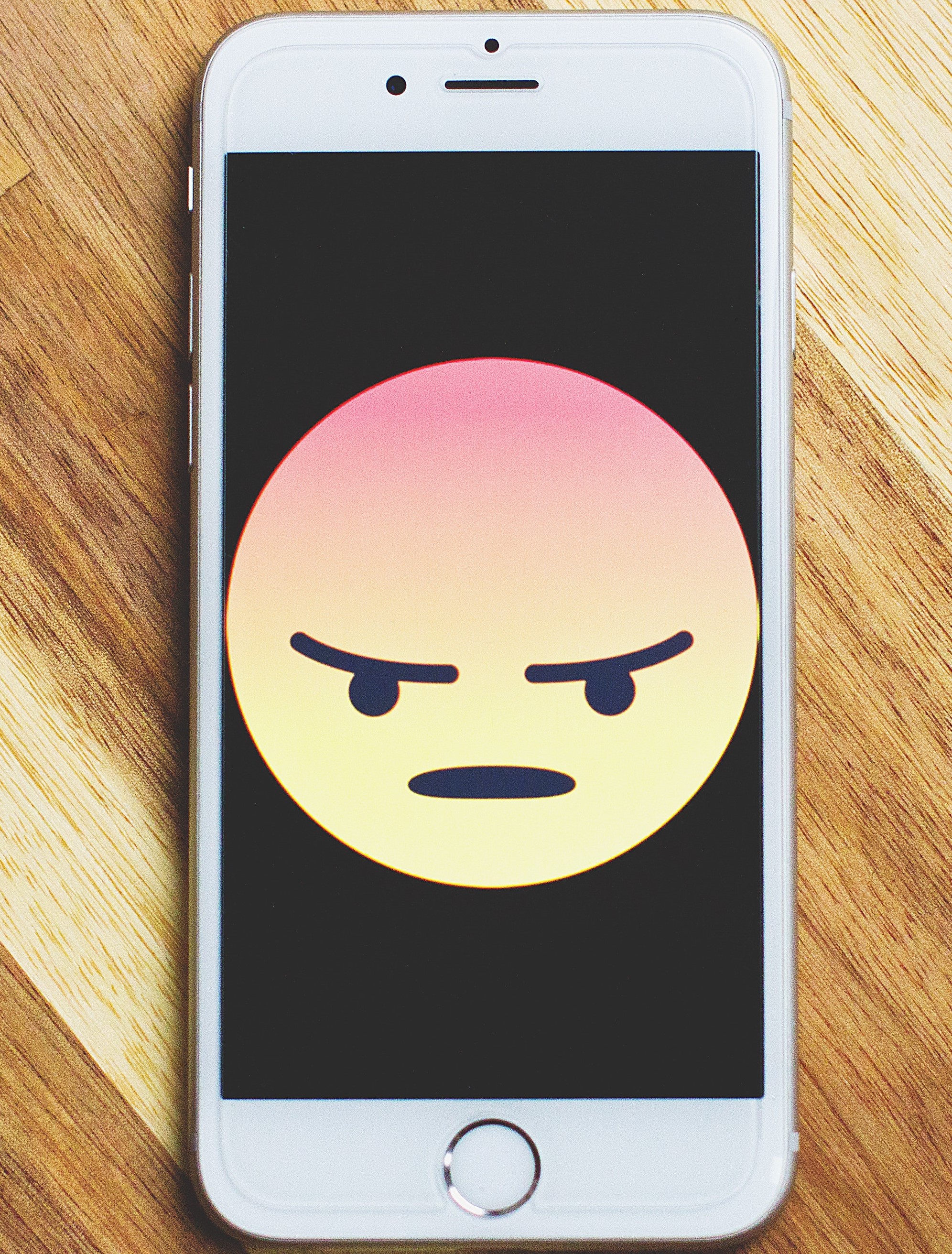 Phone with angry emoji displayed on the screen