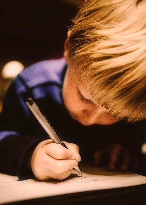 Child writing by hand with pencil