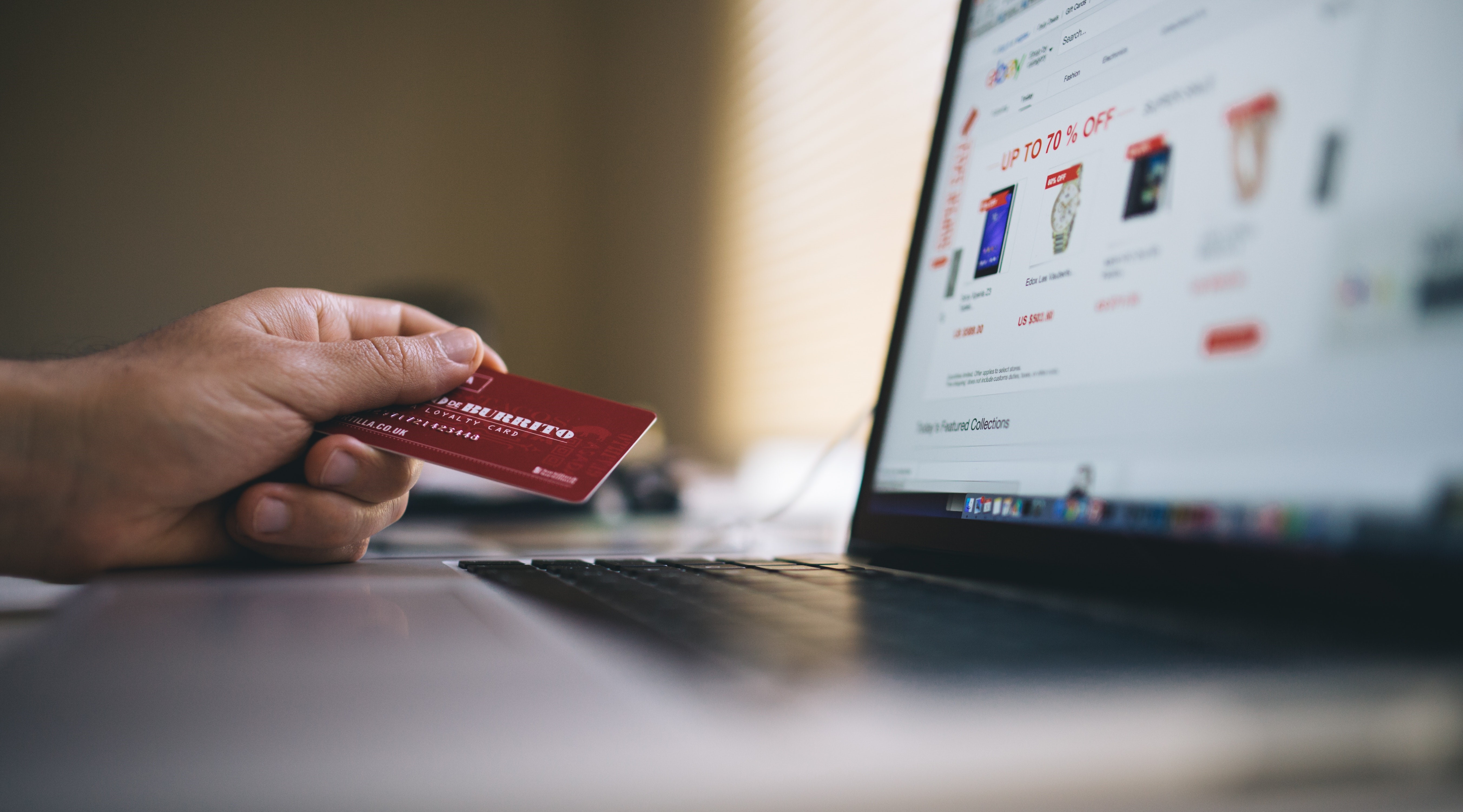 A computer screen with a person holding a bank card indicating that they are preparing to buy something online. A computer screen with a person holding a bank card indicating that they are preparing to buy something online.