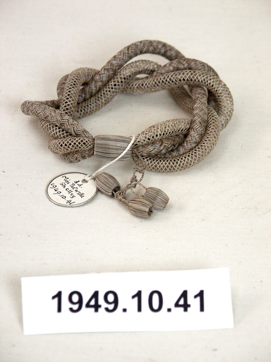 A bracelet fashioned from plaited and netted grey human hair of a deceased.