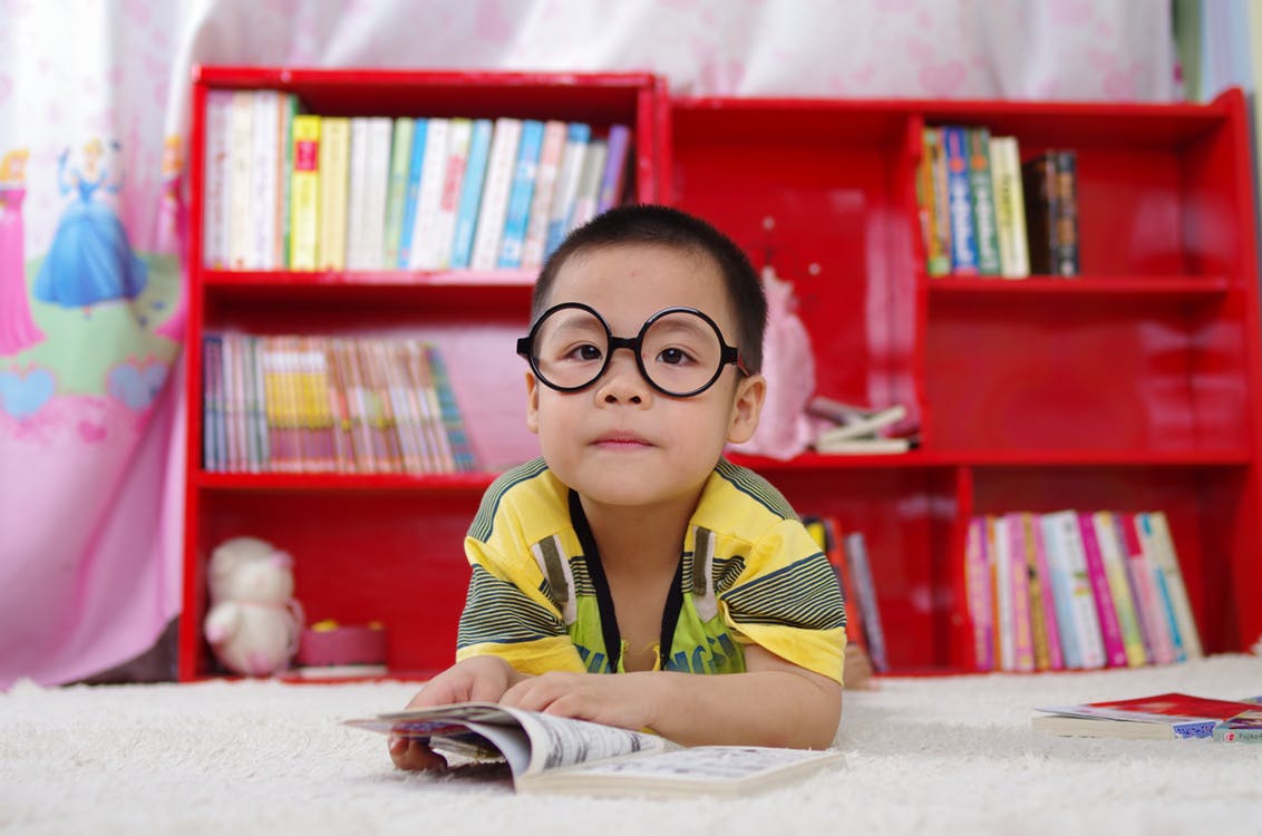 Child in a library reading a book.