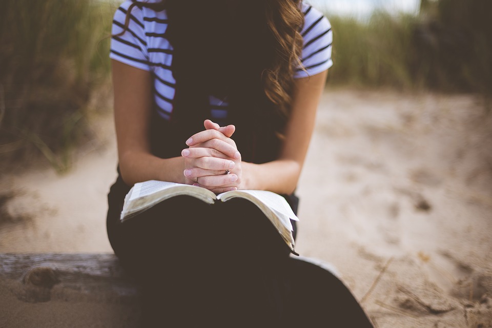 A girl praying on the beach. 